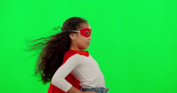 Girl kid, superhero and green screen with mask, strong and justice with hands on hips for mockup. Young female child, power and portrait with confidence, red cape and stop crime by studio background. - Footage, Video