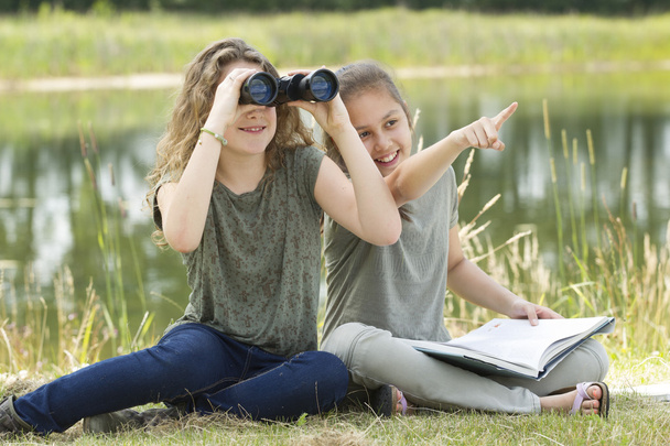 Pretty young girl exploring the environment with a binocular - Photo, Image