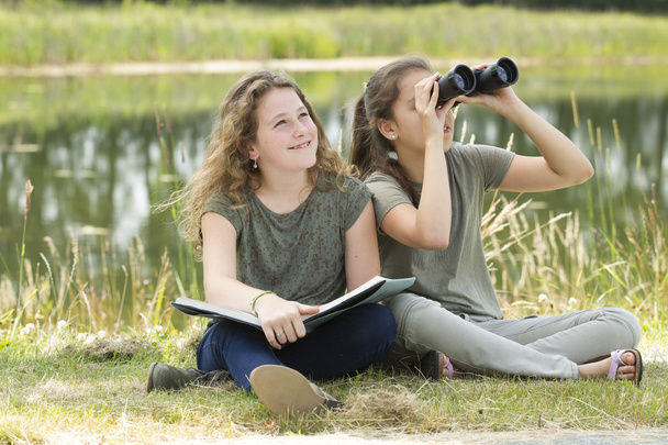 Kaunis nuori tyttö tutkii ympäristöä kiikarilla
 - Valokuva, kuva