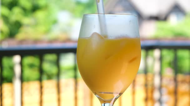 Апельсиновый сок в прозрачном стакане, наполненном кубиками льда Крупным планом меня, перемешивающего мякоть в апельсиновом соке, в замедленной съемке. Высококачественные 4k кадры - Кадры, видео
