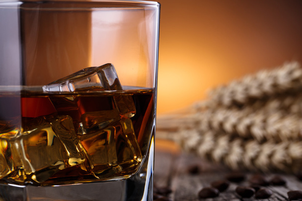 Glazen voor whisky met ijs en tarwe op een houten tafel. - Foto, afbeelding