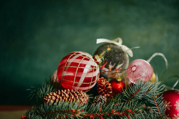 Різдвяна композиція з ялинковими гілками, кульками та різдвяними прикрасами на темному фоні - Фото, зображення