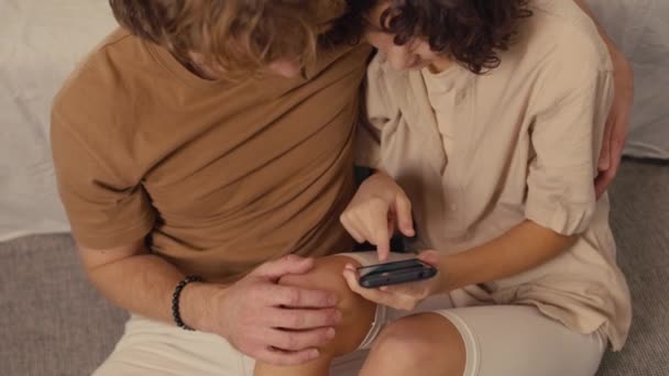 Vue aérienne de deux jeunes gens cherchant des informations à l'aide du téléphone dans les mains d'une femme aux cheveux bouclés - Séquence, vidéo