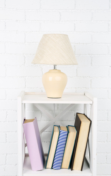 Wooden shelf with books and lamp on brick wall background - Foto, immagini