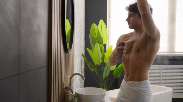 Caucasiano muscular nu homem masculino procedimento de higiene aplicando axila spray olhando no espelho em casa de banho aplicar desodorizante aroma fresco antitranspirante cosméticos suor prevenção corpo cuidados com a pele - Filmagem, Vídeo