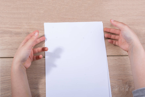 Hand holding sheets of paper on a wooden background - Photo, Image