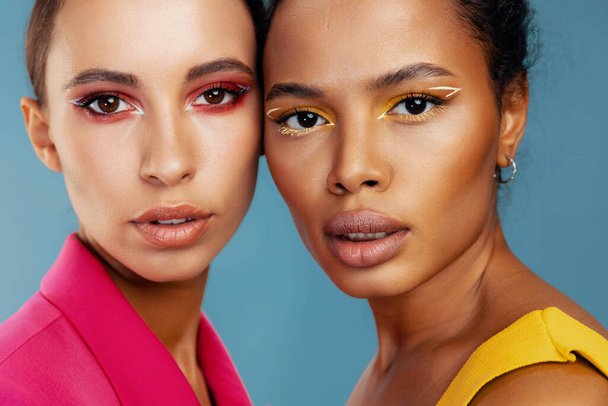 Γυναίκα μοντέλο bodycare ομορφιά όμορφο δέρμα ελκυστικό πολύχρωμο αφρικανικό δύο πρόσωπο αμερικανικό κίτρινο λάμψη μικτή ευτυχισμένη φυλή πορτρέτο make-up στούντιο μαζί - Φωτογραφία, εικόνα