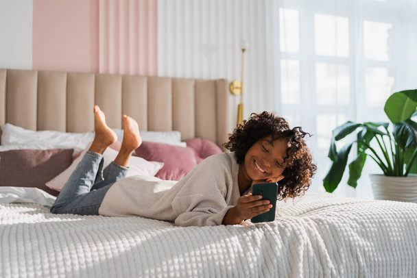 African girl holding smartphone touch screen typing scroll page at home. Woman with cell phone surfing internet using social media apps playing game. Shopping online Internet news cellphone addiction - Valokuva, kuva