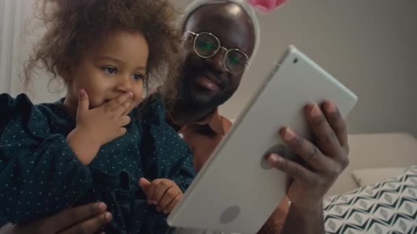 Papà e sua figlia seduti nel loro salotto, usando il loro tablet digitale per fare selfie - Filmati, video