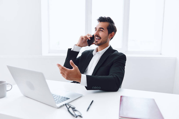Férfi életmód iroda vállalkozó menedzser laptop beszélni telefon fiatal portré technológia végrehajtó munkahely számítógép mosolyog vonzó üzletember üzleti keres professzionális - Fotó, kép