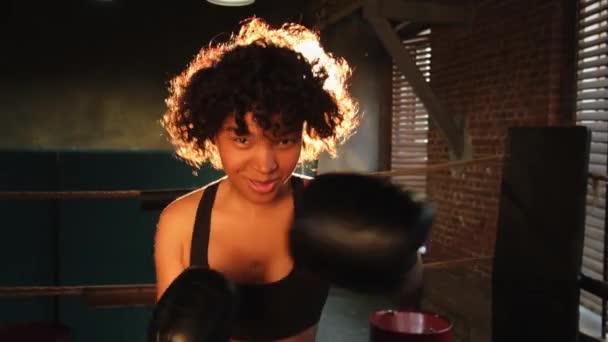 Frauen Selbstverteidigung Girl Power. Afroamerikanische Kämpferin schlägt mit Boxhandschuhen in die Kamera. Ein gesundes starkes Mädchen, das Trainingsschläge schlägt, sieht konzentriert gerade aus. Fittes Körpertraining - Filmmaterial, Video