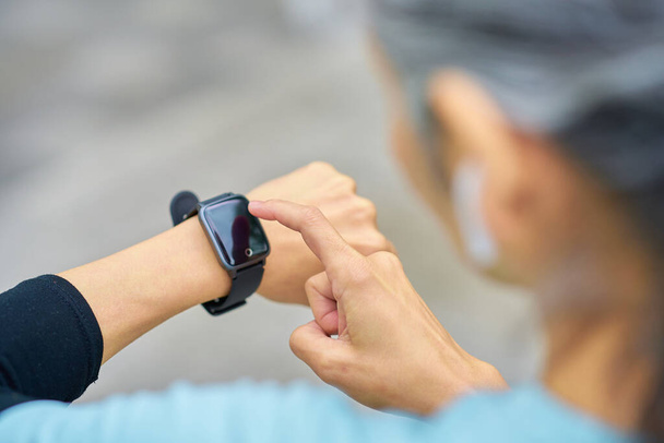 Hand of a senior woman operating a smartwatch outdoors - Photo, Image