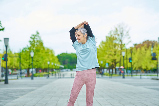 Usmívající se starší žena cvičení venku - Fotografie, Obrázek
