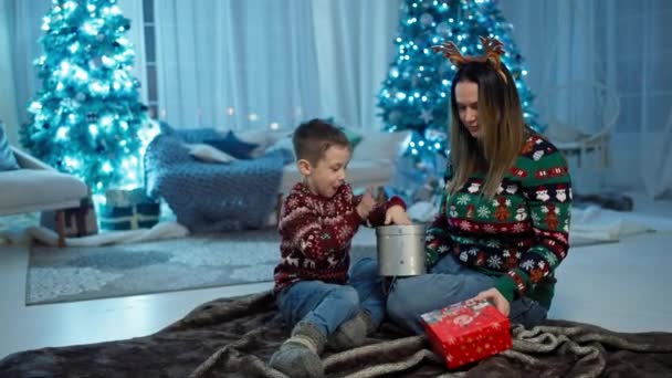 Заколдованные подарки: Счастливый мальчик разворачивает рождественские подарки рядом с Три, Санта-Клаусом, Смилсом и удивленной Джой. Высококачественные 4k кадры - Кадры, видео