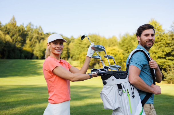 Взаимодействие: женщина выбирает клюшку из мешка для гольфа - Фото, изображение