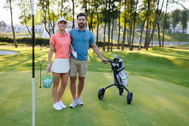 Aktives junges Paar beim Golfplatzabschluss mit Schlägertasche - Foto, Bild
