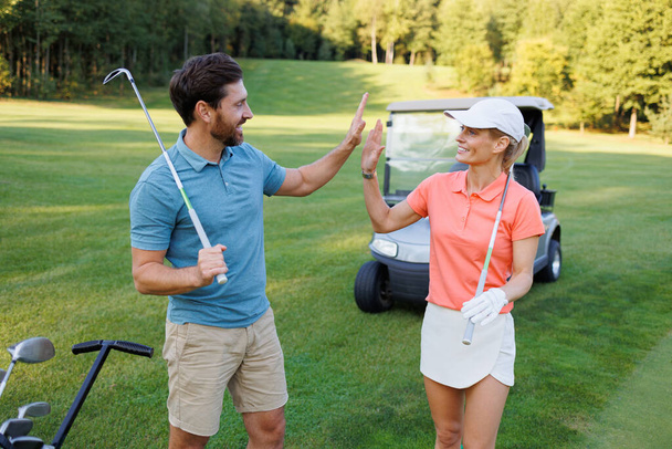 Moment triomphant : Jeune couple High Fiving sur le terrain de golf - Photo, image