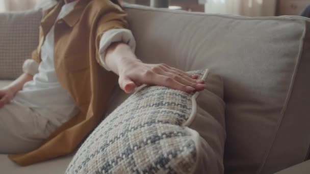 Selectieve focus op lichtgekleurd kussen op bank in meubelzaak waar onherkenbare vrouwelijke klant het recenseert - Video