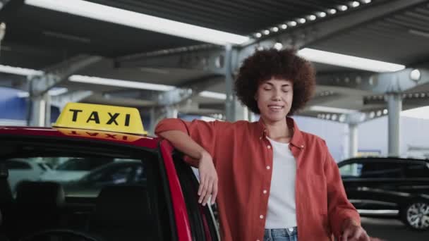 Szczęśliwa Afroamerykanka taksówkarz pokazuje ok gest podczas pozowania w pobliżu samochodu. Koncepcja samochodu służbowego. Zwolniony ruch - Materiał filmowy, wideo