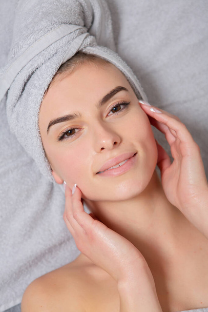Retrato de uma bela jovem mulher com toalha na cabeça.Linda jovem mulher recebendo massagem facial no salão de spa. Tratamento da beleza. - Foto, Imagem