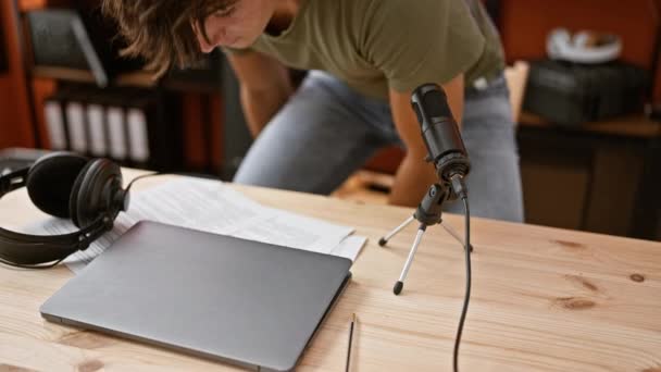 Jovem adolescente hispânico transmitindo notícias ao vivo, repórter de rádio falando no ar como ele abre laptop dentro do estúdio - Filmagem, Vídeo