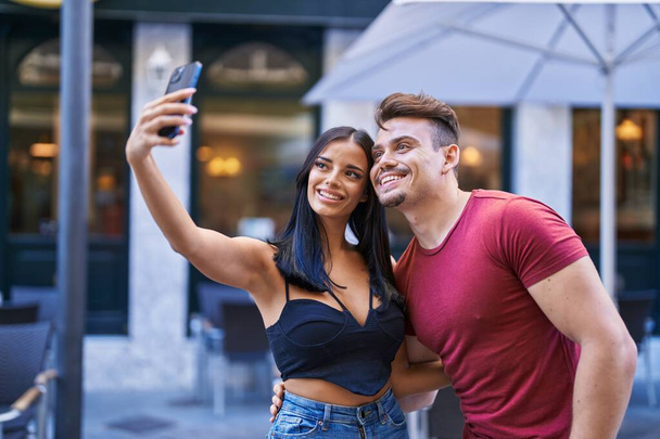 Kadın ve erkek güler yüzlü kahve dükkanının terasında akıllı telefondan selfie çekerler. - Fotoğraf, Görsel