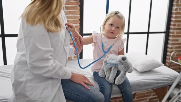 Чарівна дитина грає з лікарем, використовуючи стетоскоп у клініці, найкращий момент у дитячій охороні здоров'я - Кадри, відео