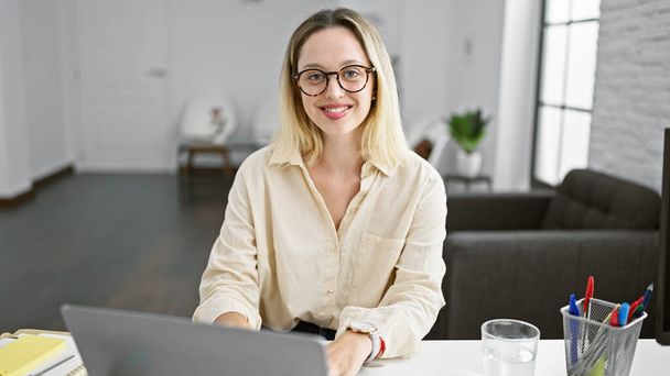 Giovane donna bionda che lavora con il computer portatile che lavora in ufficio - Foto, immagini