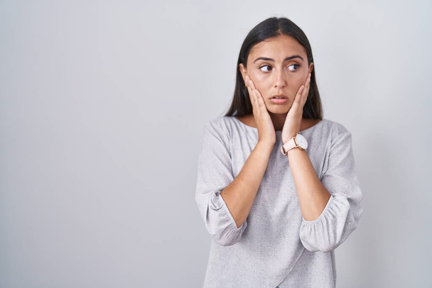 Young hispanic woman standing over white background tired hands covering face, depression and sadness, upset and irritated for problem  - Foto, immagini