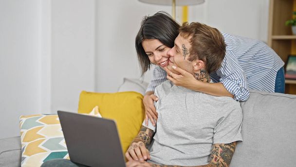 Casal bonito abraçando uns aos outros usando laptop em casa - Foto, Imagem
