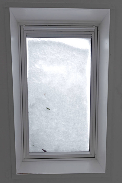 Vista a través de la ventana del techo cubierta por nieve derretida desde el interior del edificio, enfoque selectivo - Foto, imagen