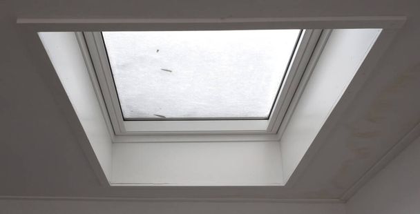 Vista a través de la ventana del techo cubierta por nieve derretida desde el interior del edificio, enfoque selectivo - Foto, imagen
