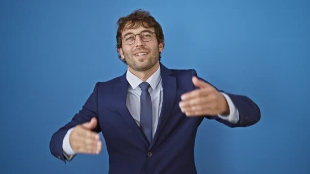 Vrolijke, jonge man die vreugdevolle ogen met handen bedekt, een leuk, blind spel onthullend in zijn gekleed zakenpak, geïsoleerd op een levendige blauwe achtergrond - Video