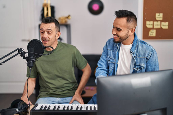 Two men musicians singing song playing piano at music studio - Photo, Image