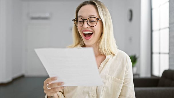 jong blond vrouw zakenman lezen document verrast op het kantoor - Foto, afbeelding