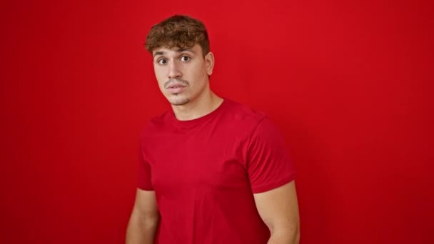 Oh wauw! prachtig portret van een jonge, knappe Spaanse man uiten ongelooflijke verrassing, geïsoleerd staan over een levendige rode achtergrond. - Video
