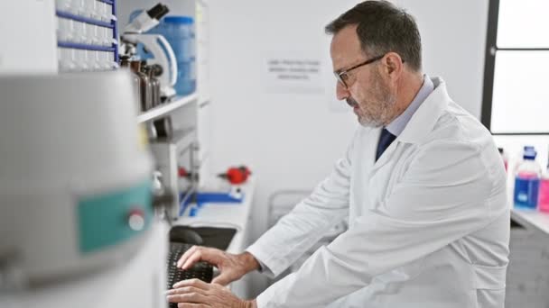 Soustředěný muž středního věku s šedivými vlasy, vědec pilně pracující u svého počítače v laboratoři, si sundá brýle v zamyšleném objevu. - Záběry, video