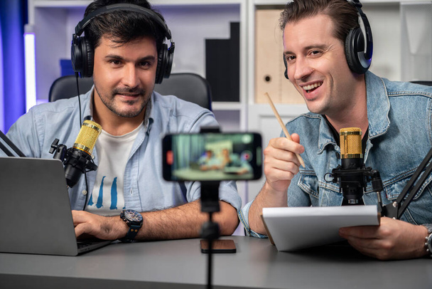 Host channel of creative broadcaster living by smartphone in positive podcast with special guest in list script to advice listeners, wearing headsets, using mic radio record at studio. Sellable. - Fotografie, Obrázek