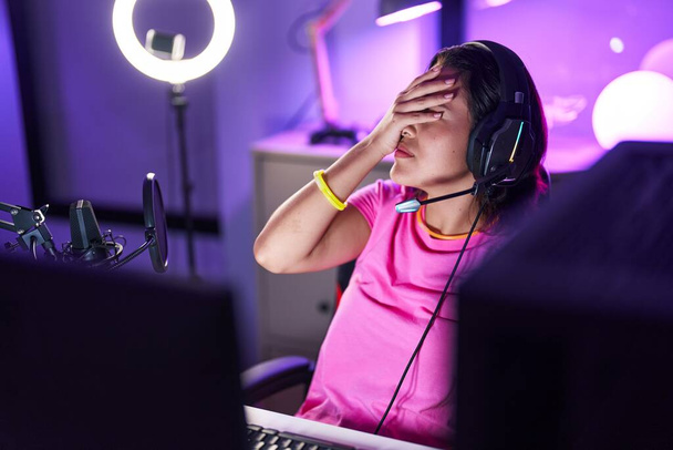 Молода іспаномовна жінка стример підкреслив, використовуючи комп'ютер в ігровій кімнаті
 - Фото, зображення