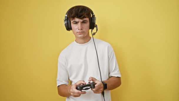 Euforische jonge Latijns-Amerikaanse tiener borrelen van vreugde, vieren zijn online gaming overwinning, volledig geabsorbeerd, comfortabel met behulp van geavanceerde technologie, geïsoleerd tegen een levendige gele achtergrond - Video