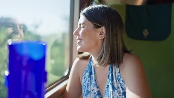 Смолящая в окно городской электрички - красивая женщина, сидящая в городском метро, веселая, глядя в окно поезда метро во время поездки - Кадры, видео