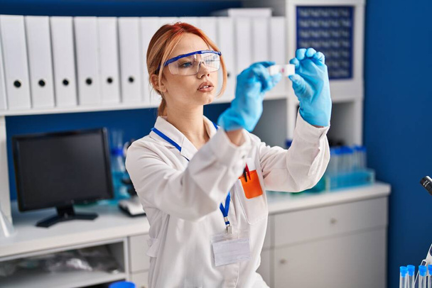 Jeune scientifique caucasienne regardant l'échantillon au laboratoire - Photo, image