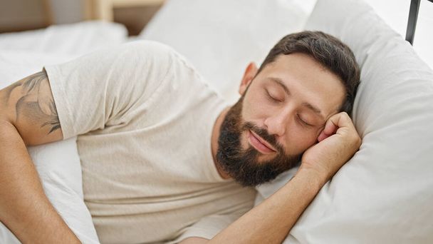 Молодой латиноамериканец лежит на кровати и спит в спальне. - Фото, изображение