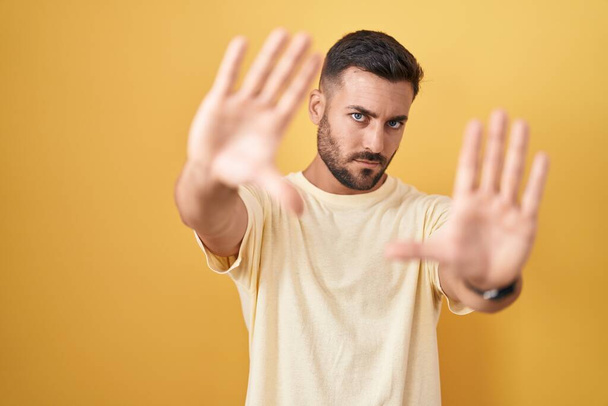Красивий іспаномовний чоловік стоїть над жовтим тлом робить рамку, використовуючи руки і пальці, перспектива камери  - Фото, зображення