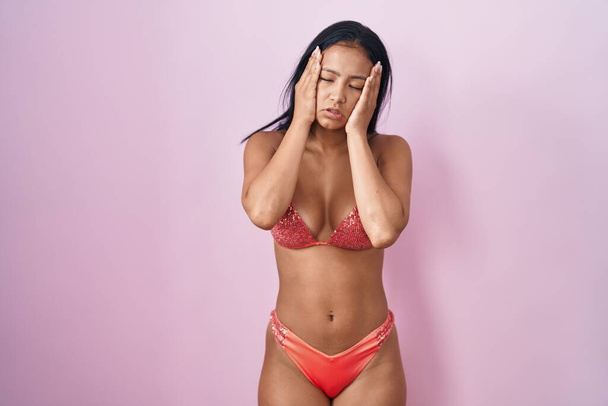 Hispanic woman wearing bikini tired hands covering face, depression and sadness, upset and irritated for problem  - Photo, Image