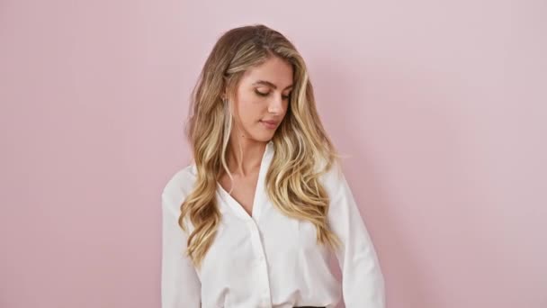 Zelfverzekerde jonge blonde vrouw in shirt, staande klaar over geïsoleerde roze achtergrond, controleren polshorloge, niet gehinderd door te laat lopen - Video