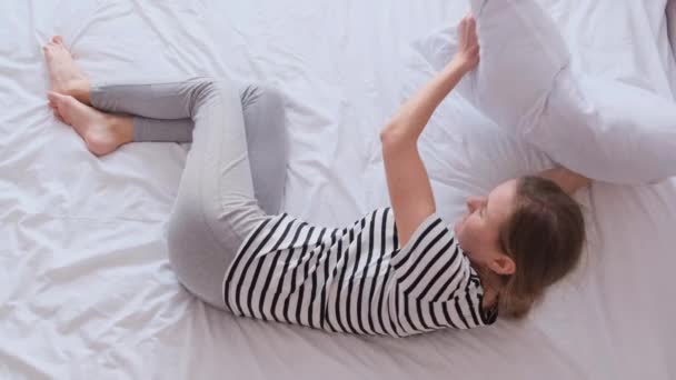 Een slapeloze vrouw ligt in bed, bedekt haar hoofd met een kussen. Concept van slapeloosheid, blinde aandoeningen als gevolg van angst of depressie. - Video