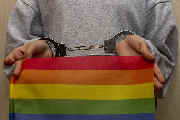 Kadın eli, polis kelepçesi, LGBT bayrağı. Kavram: Yasaklama ve zulüm, Rusya 'da özgürlük kısıtlaması. - Fotoğraf, Görsel