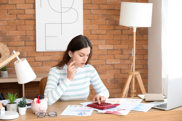 Mladá studentka sedící u stolu s mapami a počítající své finance. Koncept studentské půjčky - Fotografie, Obrázek