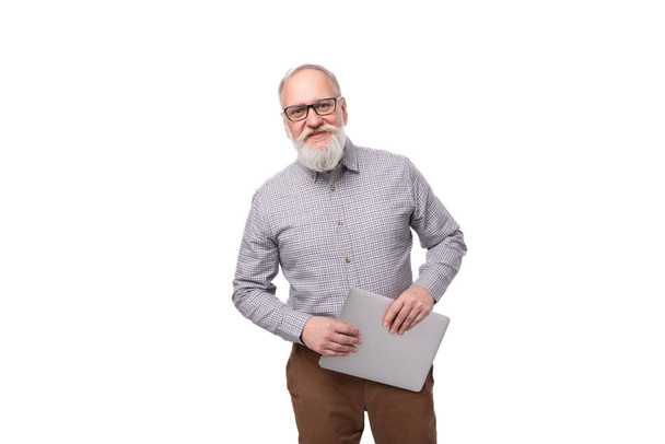 úspěšný dědeček s bílým vousem a knírem je oblečen do košile a kalhot pracujících v IT společnosti. muž držící laptop. - Fotografie, Obrázek